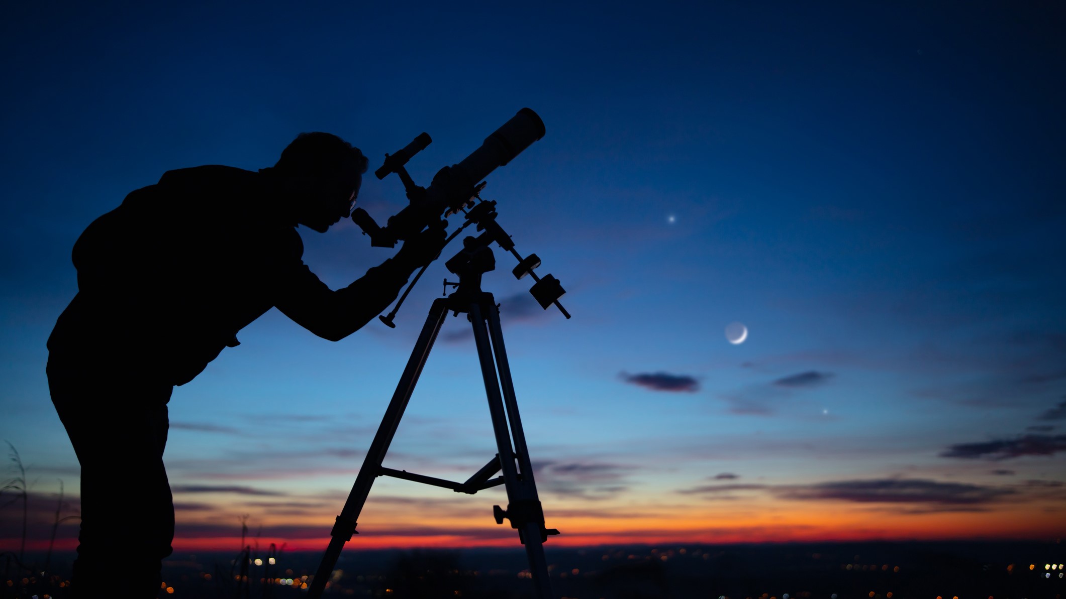 Hình bóng của một người đàn ông với kính viễn vọng nhìn lên bầu trời.